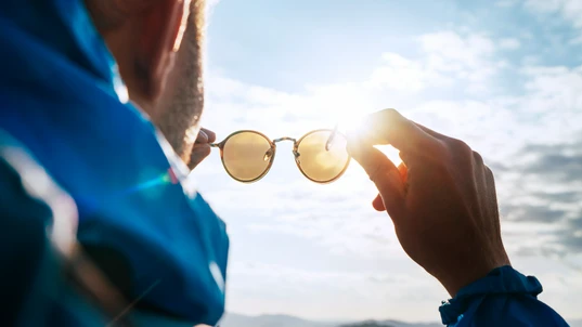 Man holding up sunglasses to the sun while hiking